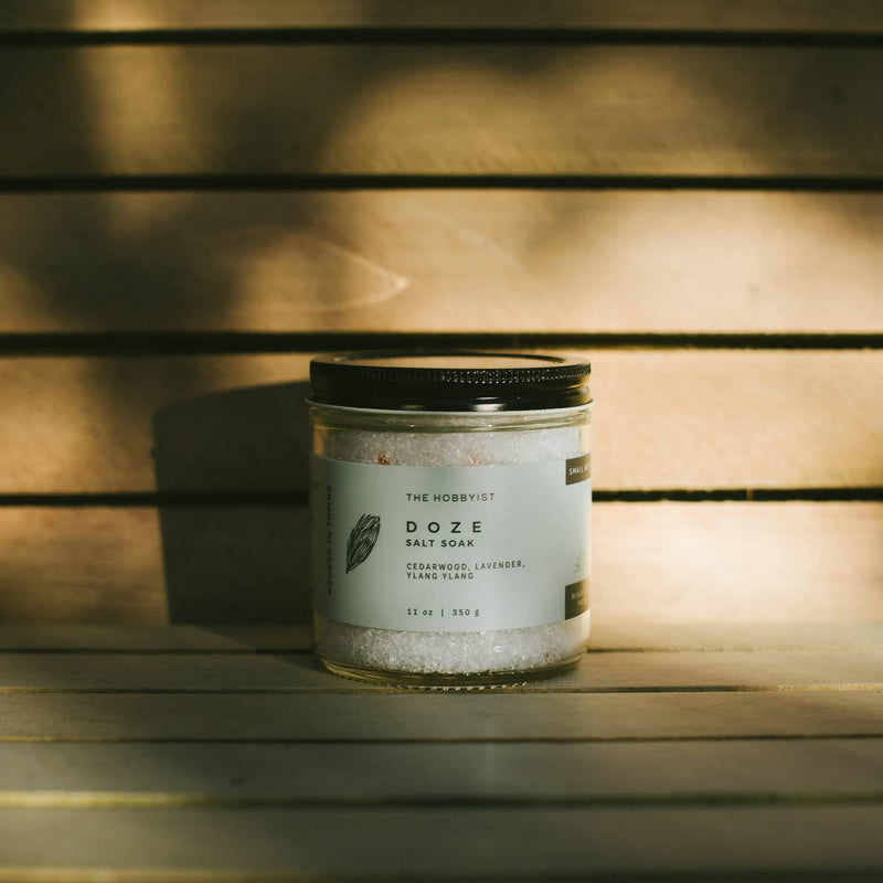 Candle jar labeled 'Doze' on a wooden surface with warm lighting