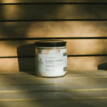 Candle labeled 'Flower Power' on a wooden surface with a warm glow